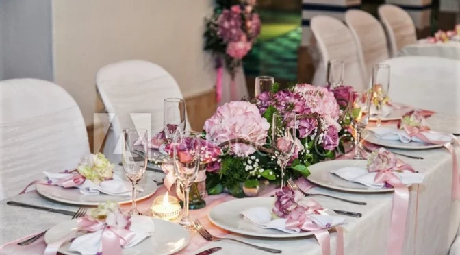 Elegant wedding table styling with pink floral centrepieces, white tableware and romantic décor.